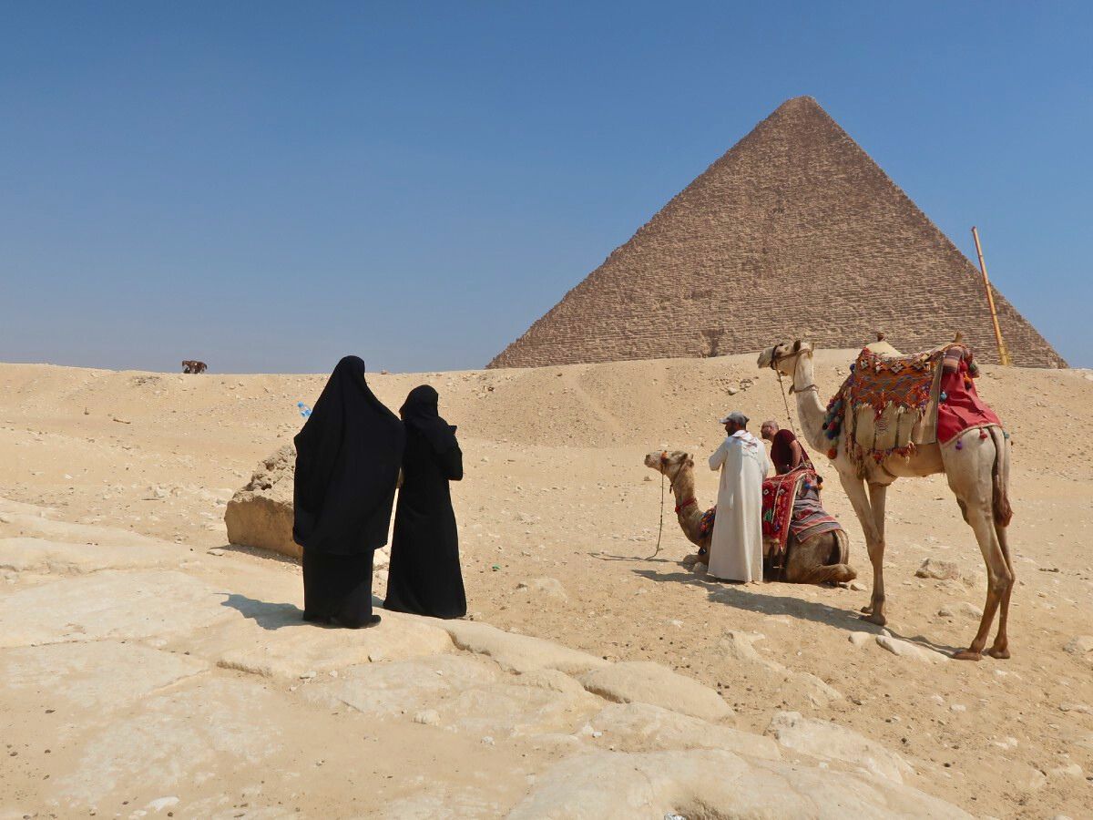 Pyramid of Giza with two camels and two women in burkas