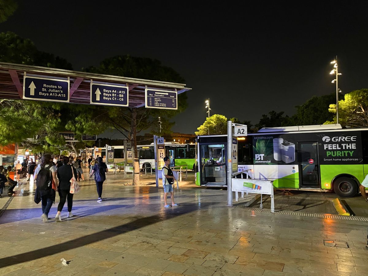 few tourists waiting for green bus at Malta bus station at night