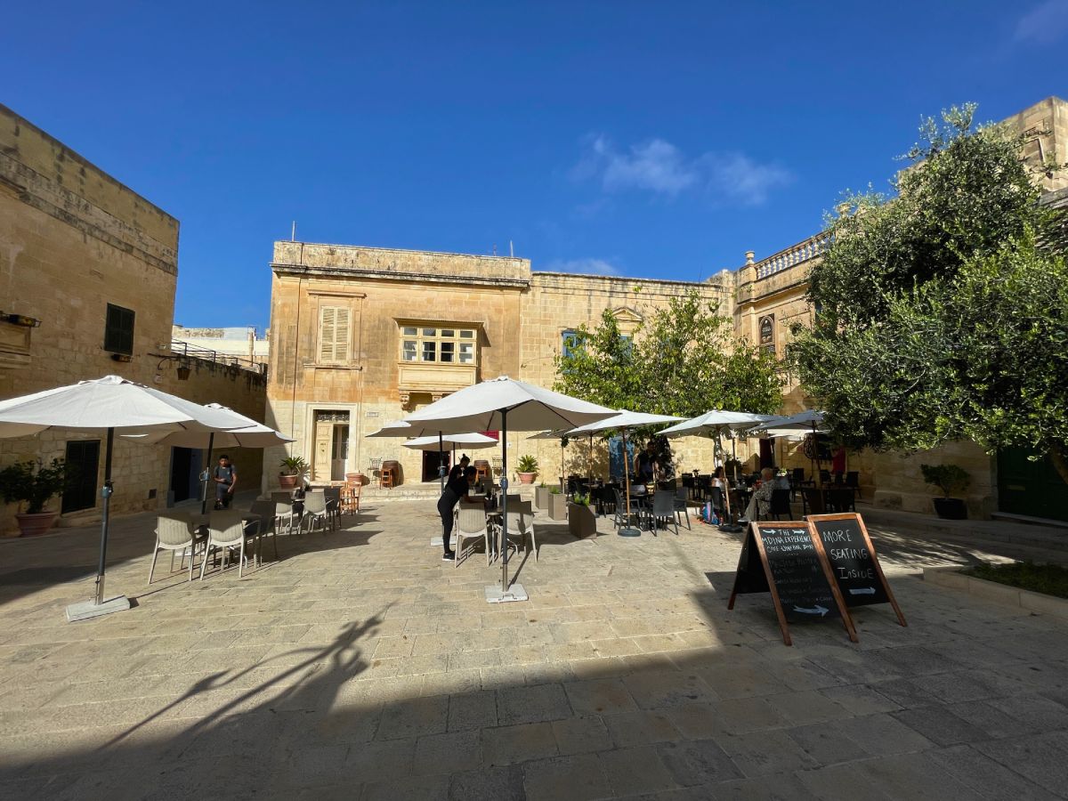 Piazza Mesquita with few people relaxing on the chairs under the umbrella