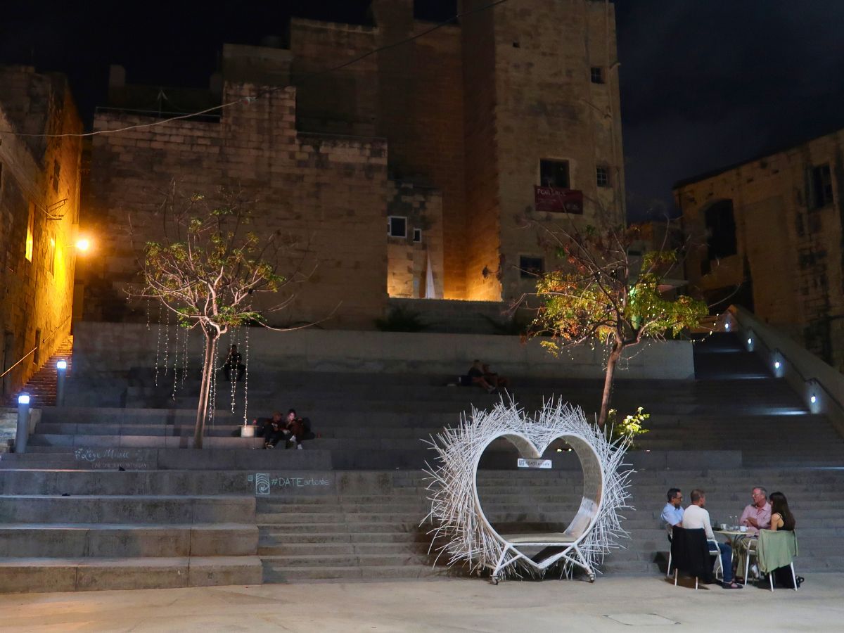 people having a drink next to the Cospicua stairs at night