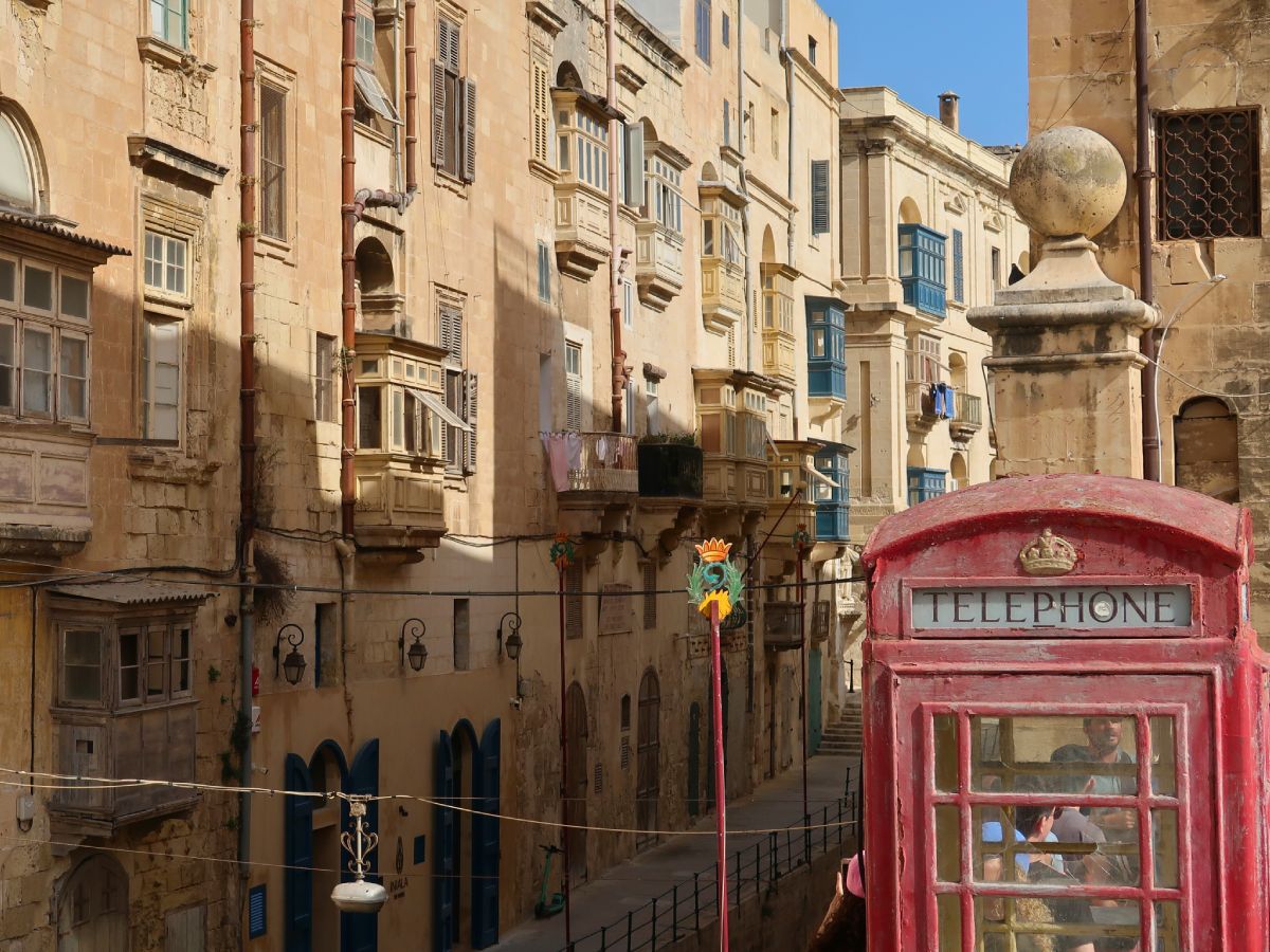 Historic building with blue and yellow balconies and red telephone booth in a british style